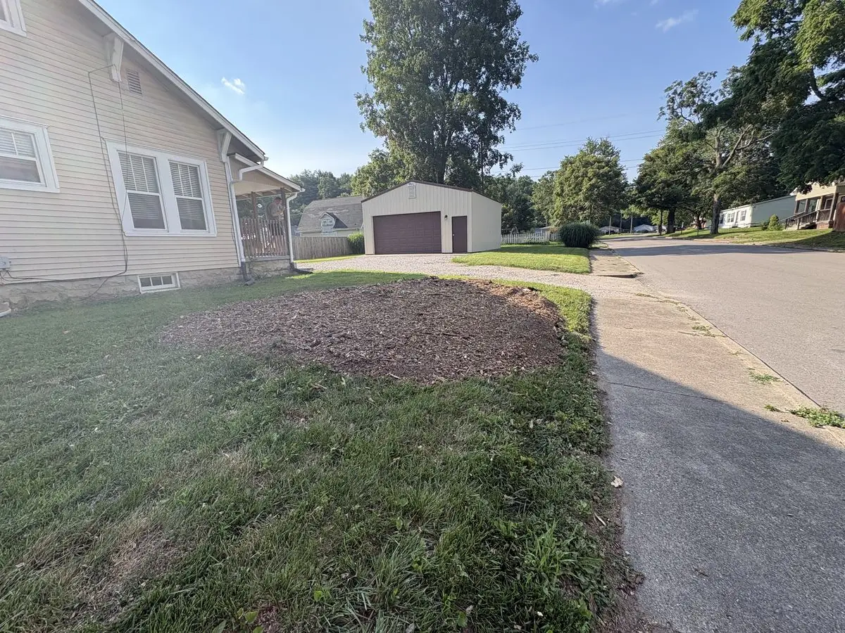 Same front yard after storm cleanup and stump grinding — stump ground below grade, grindings leveled, lawn cleared