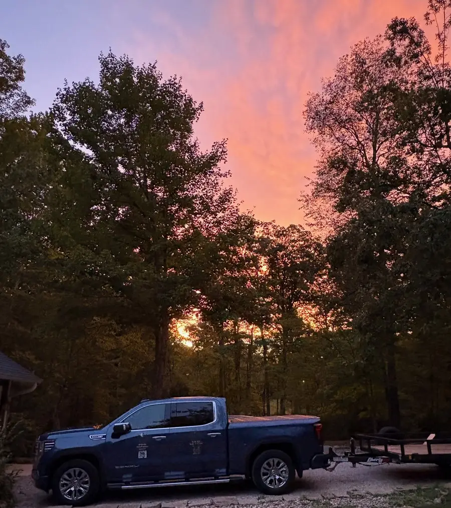 Brown County Stump Grinding and Tree Service pickup and equipment trailer parked under the trees at sunset after a day's work